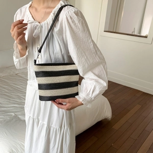 Detail of black and white striped woven tote bag with a slim black leather shoulder strap