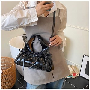 Detail of black patent leather bag with bow drawstring design and glossy finish
