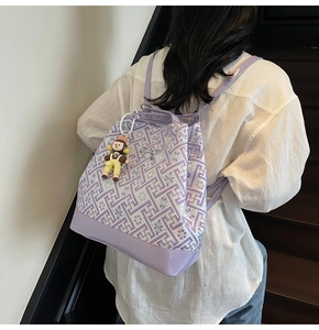 Detail of purple tote bag with geometric patterns, glossy leather trim and cute charm