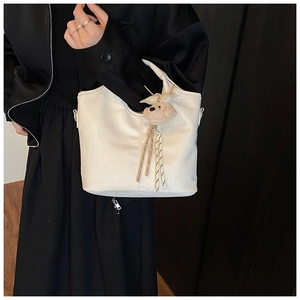 Detail of white crocodile pattern bucket bag with soft bear charm and silver hardware