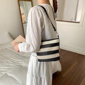 Detail of black and white striped woven tote with premium leather shoulder strap detail