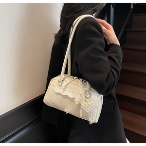 Detail of cream patent leather shoulder bag with wavy stitching and pearl heart charm
