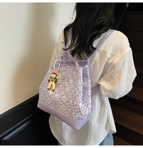 Detail view of purple floral jacquard backpack with leather trim and cartoon doll charm