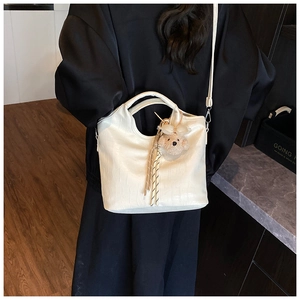Detail of white crocodile texture handbag with bear charm and silk scarf decoration
