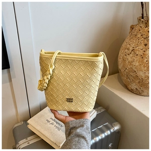 Detail of hand-woven bucket bag featuring leather texture and braided knot decoration