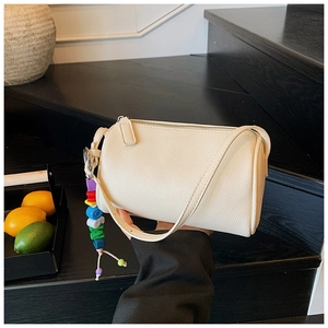 Detail view of cream lychee texture cylindrical crossbody bag with colorful bead charm