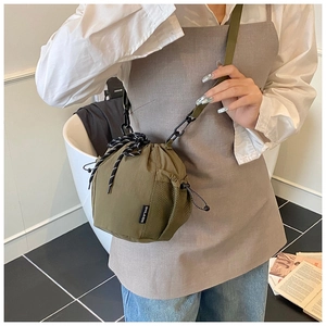 Detail of olive green nylon bucket bag featuring side mesh pocket and woven drawstring