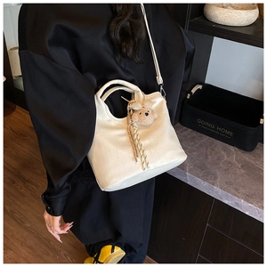 Detail shot of white crocodile pattern bucket bag with bear charm and woven cord