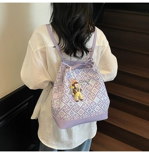 Detail of purple Greek key pattern bucket bag with bow charm and doll pendant