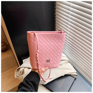 Detail of pink woven leather bucket bag featuring a decorative twisted shoulder strap