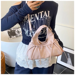 Detail of light pink patent leather handbag with bow accents and versatile straps