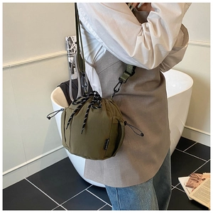 Detail of olive green nylon drawstring bucket bag with patterned rope and brand woven label