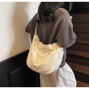 Detail view of large beige canvas tote bag with side fringe and front flap pocket