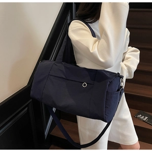 Detail of navy blue nylon travel bag with metal ring buckle and side pocket on stairs
