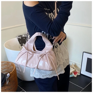 Close-up of pink glossy pleated handbag with long ribbon bows in a lifestyle setting