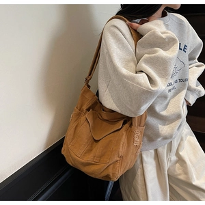 Detail of dark brown canvas crossbody bag featuring distressed raw edges and side pockets