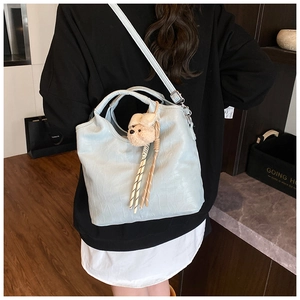 Detail of light blue faux crocodile leather bucket bag with a cute plush bear charm