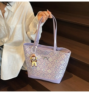 Detailed view of purple jacquard tote with bow accent and cute cartoon charm on stairs