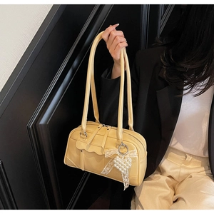 Detail of a creamy yellow retro shoulder bag with pearl heart charm and lace bow details