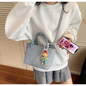 Detail of blue woven straw bucket bag featuring leather handles and a cute doll charm