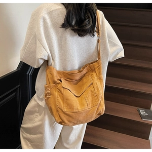 Rear view of ginger canvas crossbody bag with frayed side pockets on a model