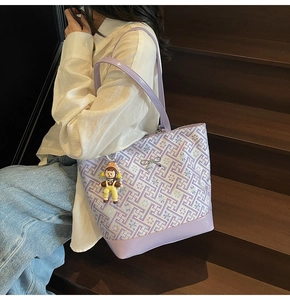 Detail of purple geometric tote bag with metallic bow and doll pendant on stairs