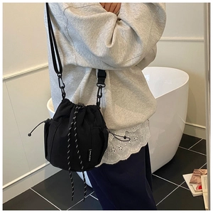 Detail of black drawstring bucket bag featuring side mesh pocket and adjustable strap