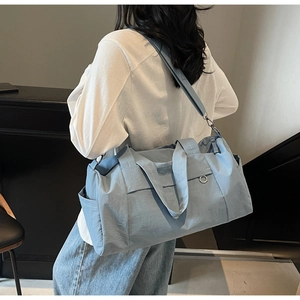 Detail view of the blue travel bag featuring reinforced handles and adjustable strap