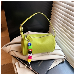 Detail of bright green cylinder bag with lychee texture leather and colorful bead charm