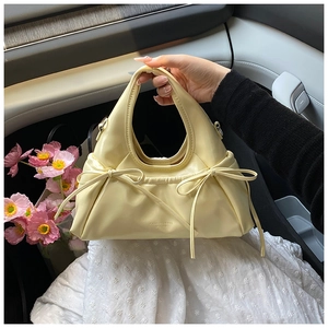 Close-up of cream yellow handbag with cloud-like pleats and delicate side bow details