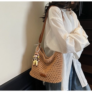 Detailed texture of hand-woven tote bag with brown leather strap and cute doll pendant