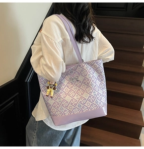 Close-up of purple geometric tote bag featuring floral embroidery and a cute doll charm
