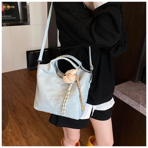 Detail of light blue faux crocodile leather tote bag with cute plush bear charm