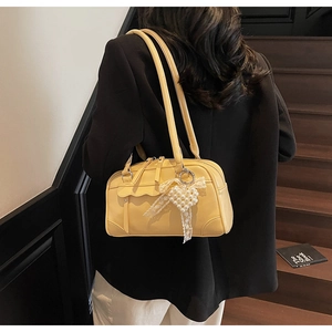 Detail of yellow bowling style shoulder bag with pearl heart and lace decorative charm