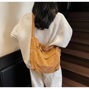 Detail of caramel canvas messenger bag with distressed edges and vintage pocket