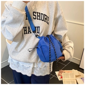 Close-up of blue drawstring bucket bag with textured fabric and patterned cord detail