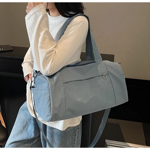 Detail of light blue waterproof travel bag showing adjustable shoulder strap and side zipper pocket