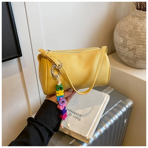 Detailed view of yellow lychee pattern cylinder bag with a colorful CHLOSU letter charm