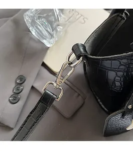 Close-up of silver metal hook and D-ring on black crocodile texture bucket bag strap