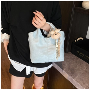 Detail of light blue crocodile texture bucket bag featuring a cute plush bear charm