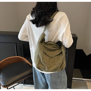 Detail view of army green canvas crossbody bag featuring vintage fringe and flap pocket
