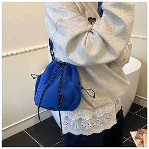 Close-up of bright blue drawstring bucket bag featuring a mesh pocket and tactical nylon texture