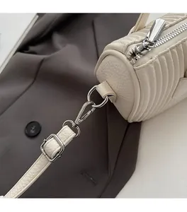 Detail of cream white lychee leather bag with shiny silver hardware and V-shaped stitching