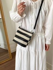 Minimalist black and white striped woven crossbody bag with slim leather shoulder strap
