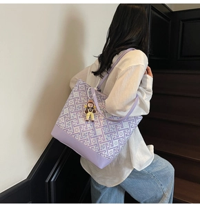 Detail view of purple geometric tote bag with cute doll charm shown on model's shoulder