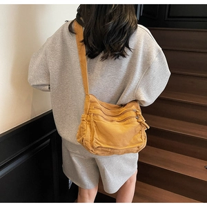 Detail view of ginger yellow canvas crossbody bag with multiple zippers and wide strap