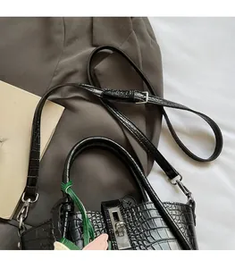 Detailed close-up of crocodile pattern handbag with silver twist lock and adjustable strap