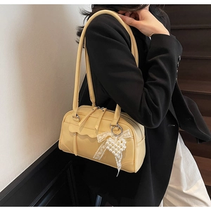 Detail of light yellow PU leather bag with white lace bow and pearl heart charm