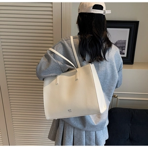Detailed view of white litchi pattern leather tote bag with MER PAI lettering and slim straps
