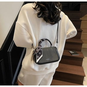 Detail of crossbody mini bag with silk scarf on handle and silver logo metal plaque